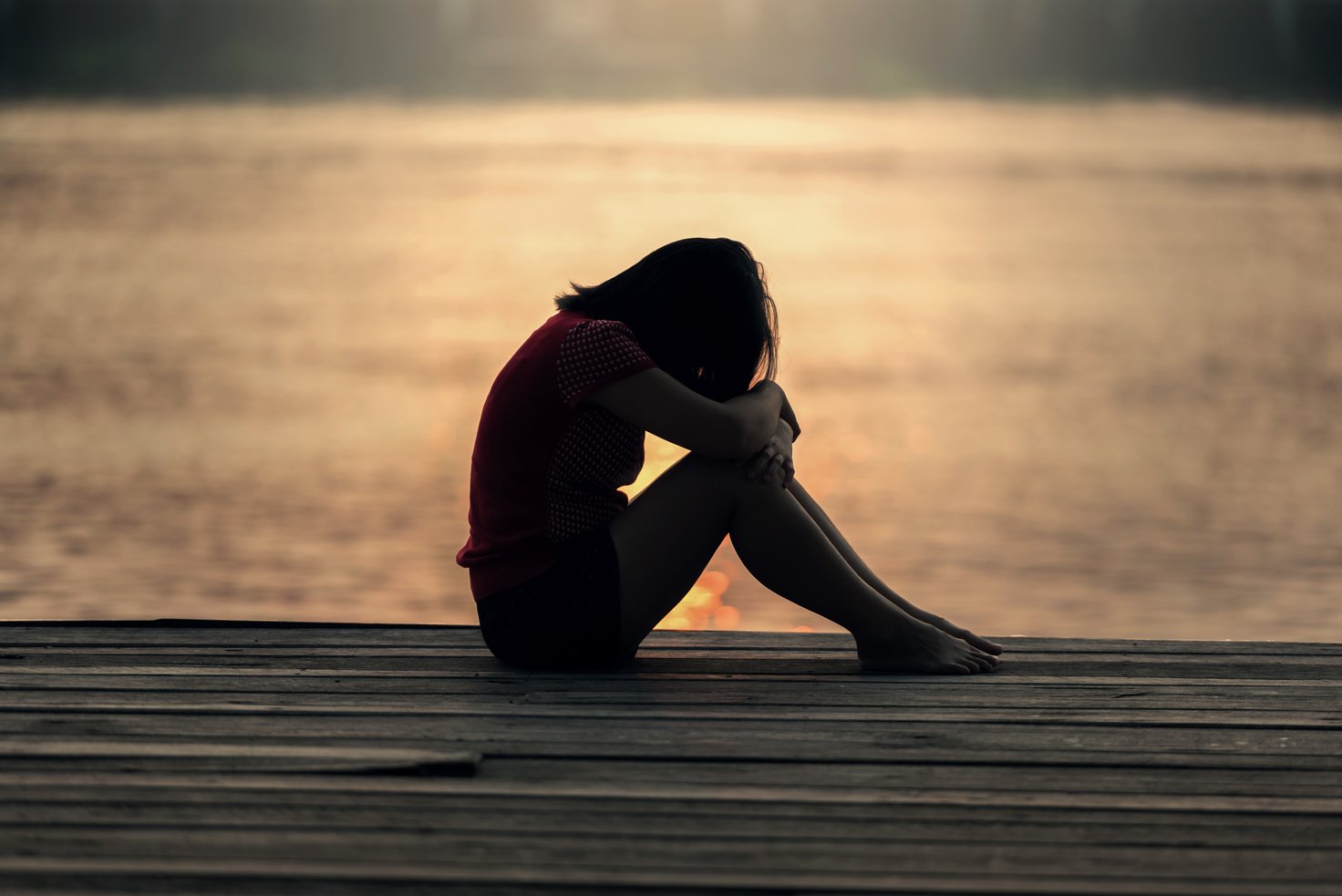 Silhouette of a Sad Girl Sitting by the Pier