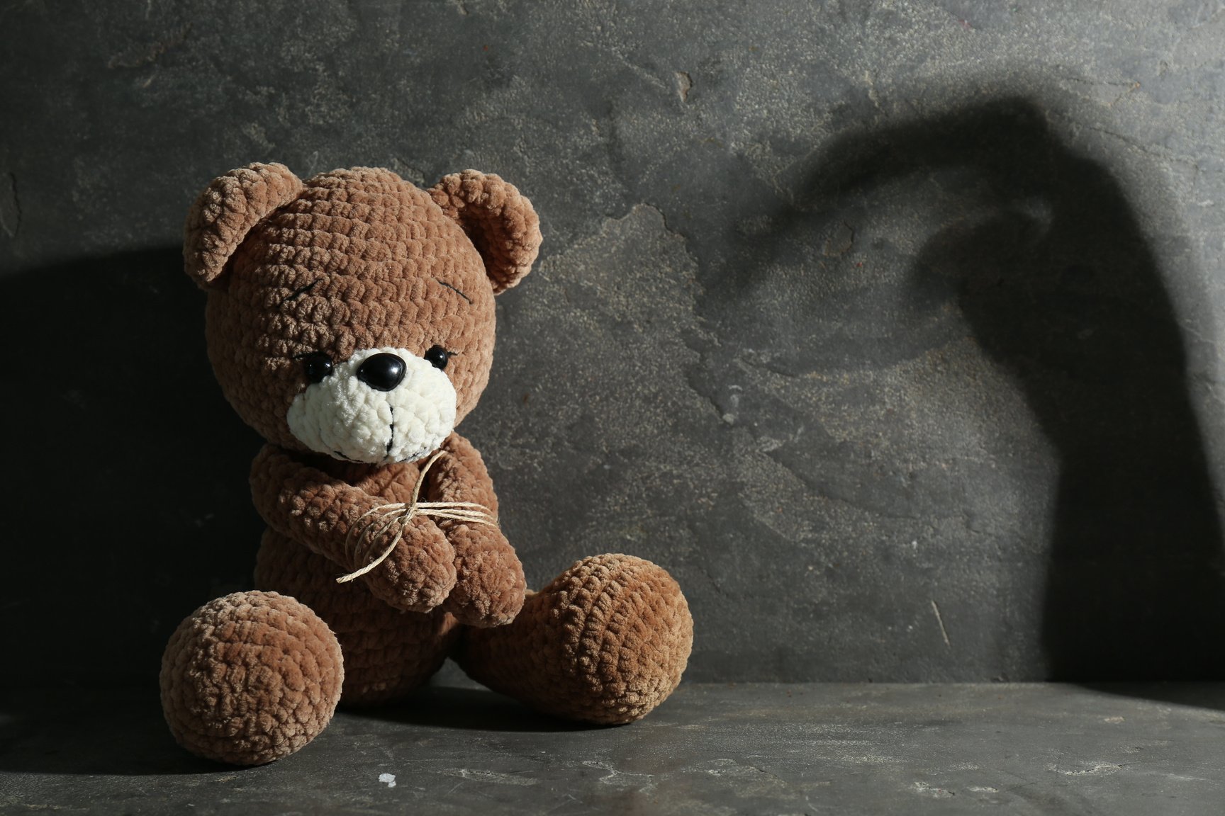 Stop Child Abuse. Tied Toy Bear and Scary Shadow in Dark Room